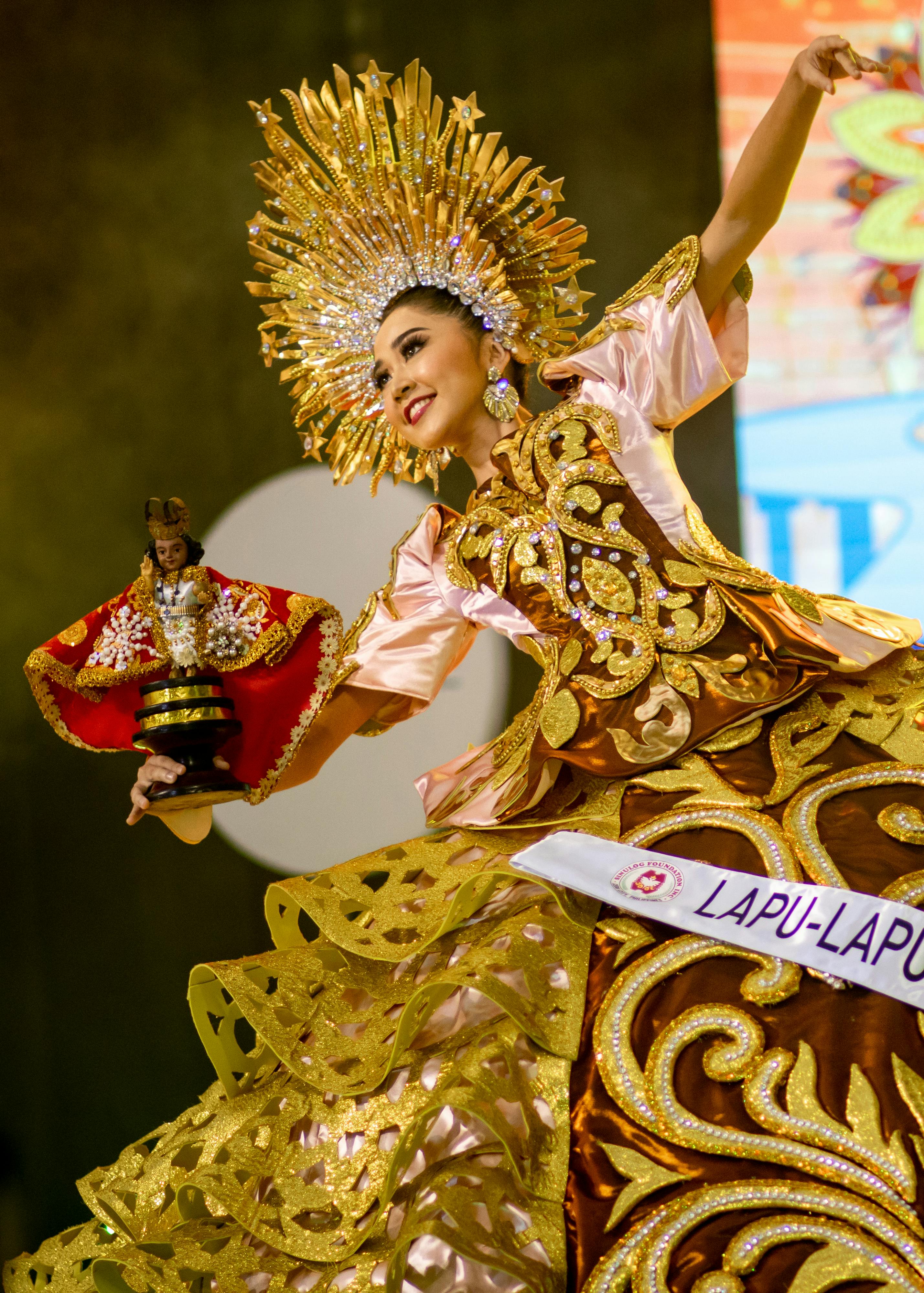 pageant contestant in ornate dress holding wooden doll