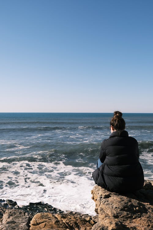 Woman Sitting on Rocks on Sea Shore