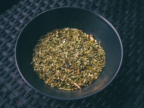 Free Fresh green herbs in a black bowl on a textured dark mat. Perfect for culinary and cooking themes. Stock Photo