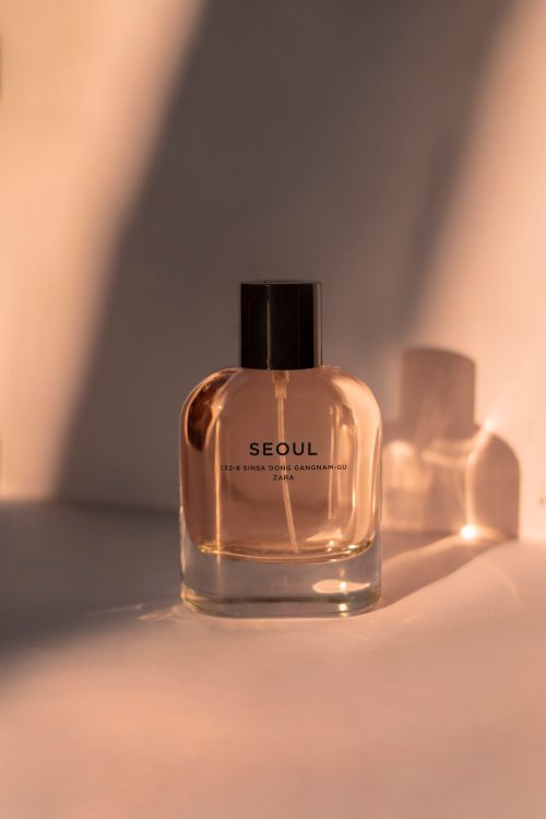 Free A sophisticated perfume bottle labeled 'Seoul', beautifully lit with warm tones and shadows. Stock Photo