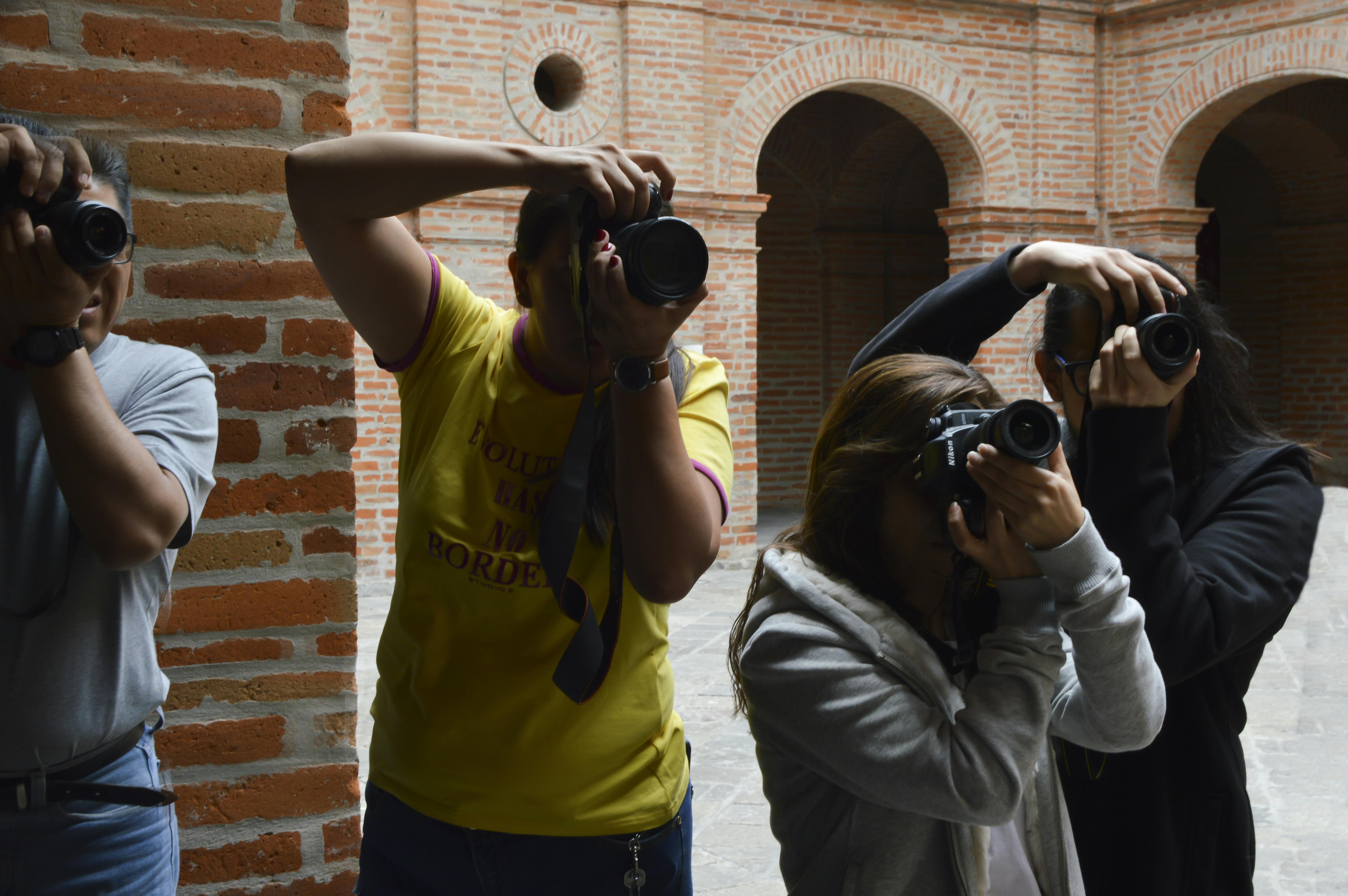 Photographers taking pictures inside a brick building with DSLR cameras.