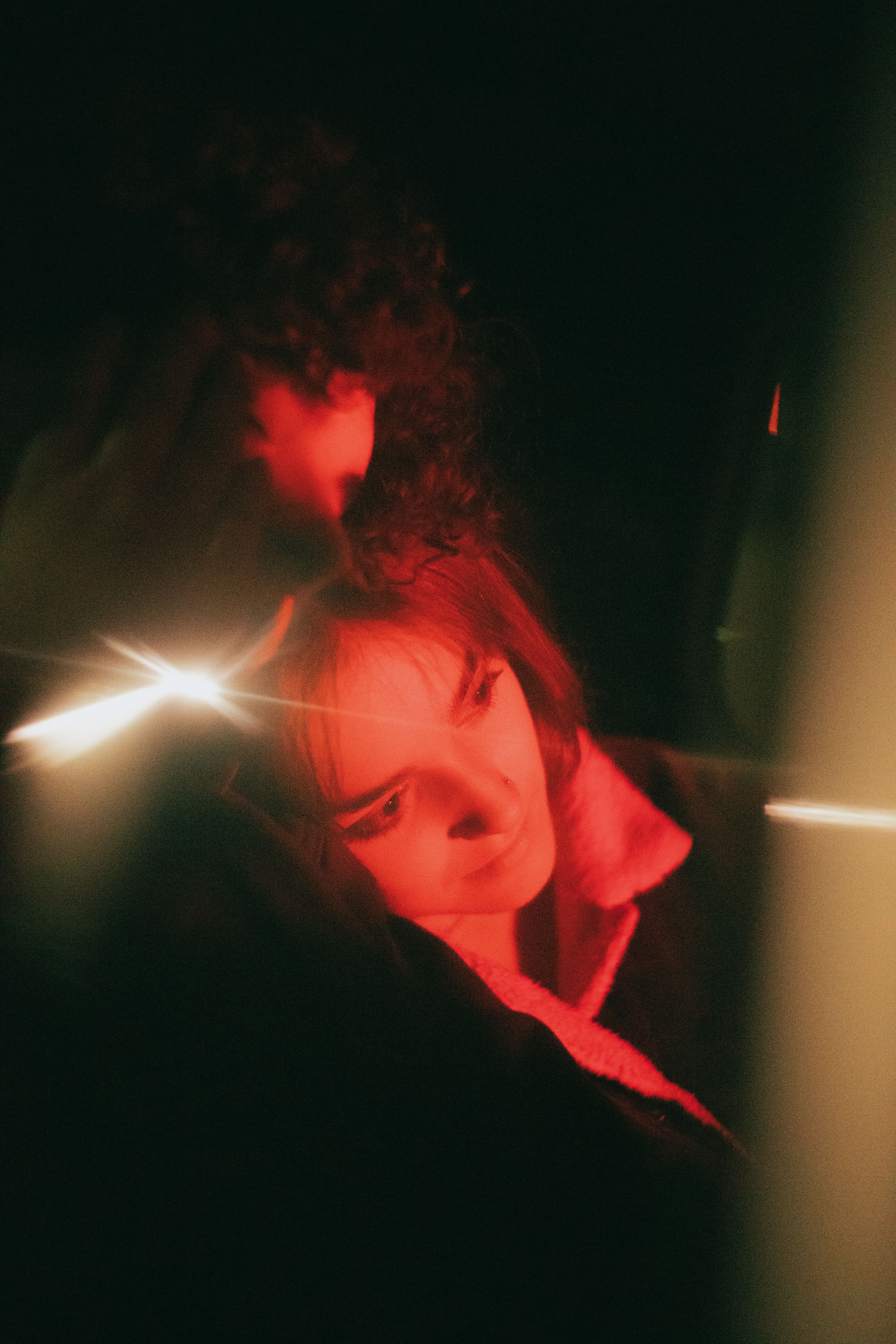 Intimate couple portrait with dramatic red lighting, creating a moody and artistic atmosphere.