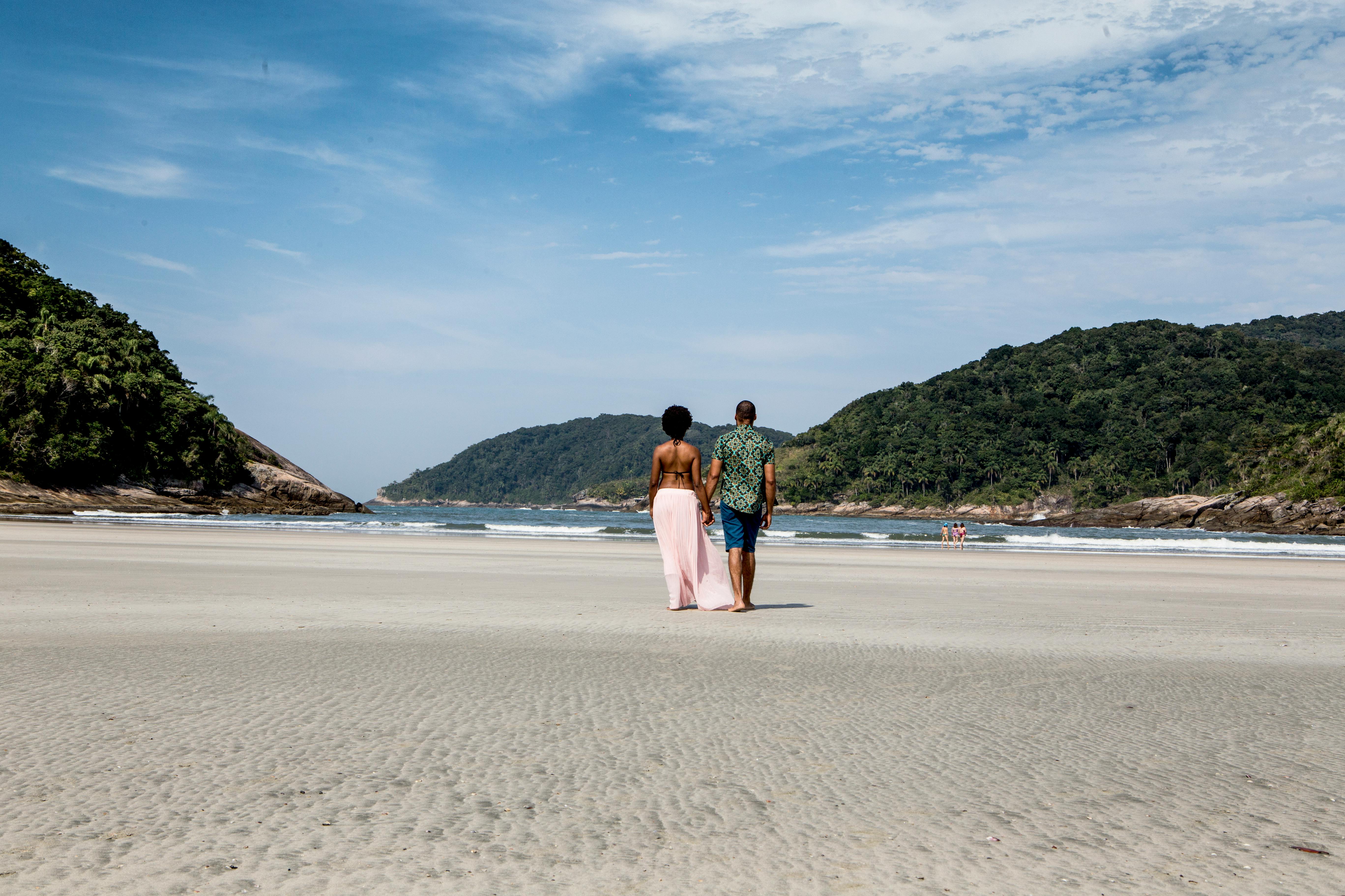 a couple walking on the beach in front of the ocean