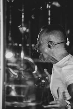 Black and white photo of a man shouting passionately with earphones, captured indoors.