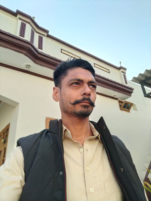 Free Low angle shot of a man with a moustache posing in front of a building. Stock Photo