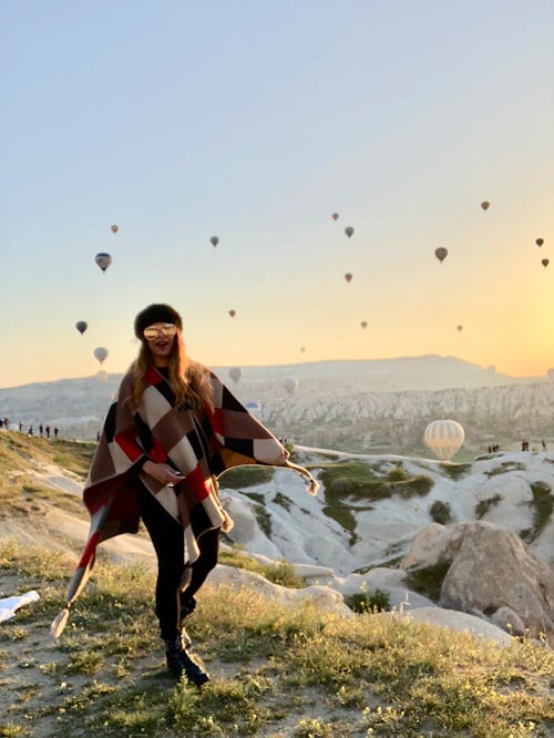 Woman Standing on Hill With Flying Hot-Air Balloons at the Back