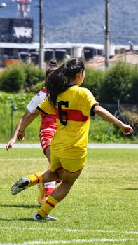 Back view of a women's soccer match, players in action on a sunny day.
