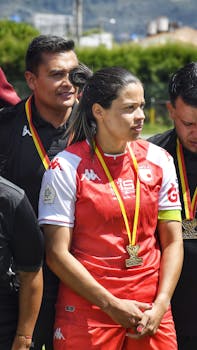 Football players in red uniforms proudly display their medals outdoors after a victorious match.