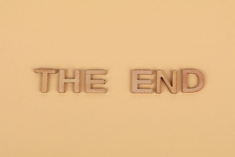 A Sign The End From Wooden Letters On Plain Background 