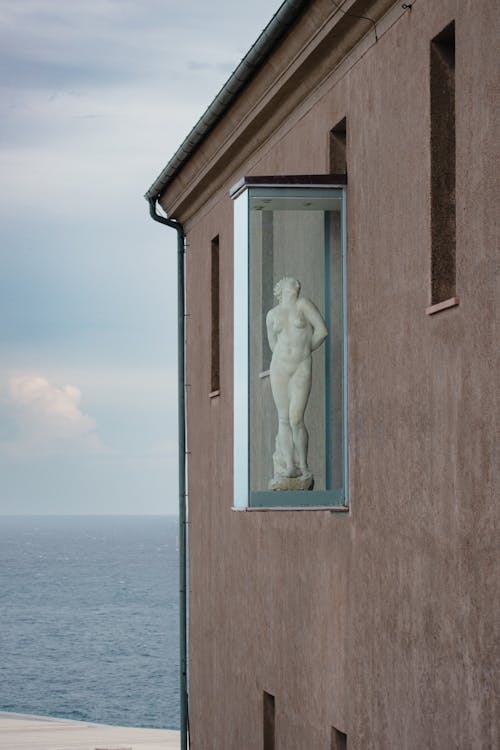 A Sculpture in a Glass Cabinet on a Facade of a Building near the Sea 