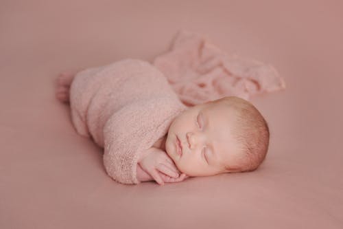 A Newborn Baby Wrapped in a Pink Blanket 