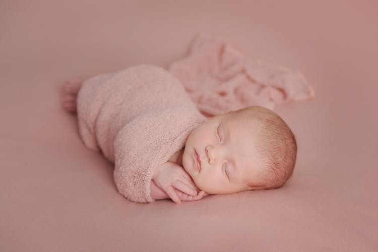 A Newborn Baby Wrapped In A Pink Blanket 