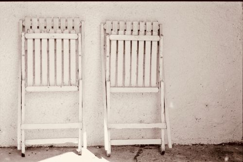 Free Two vintage wooden folding chairs leaned against a textured white wall. Stock Photo