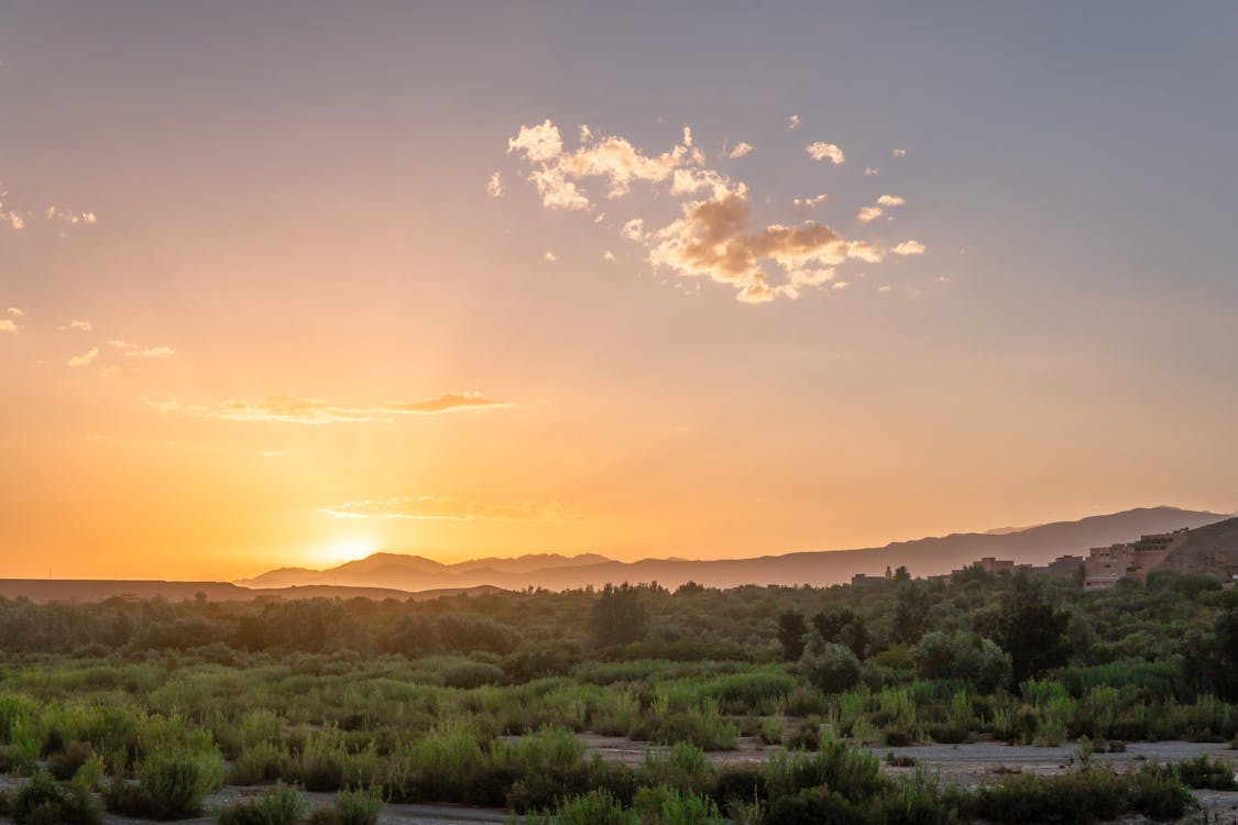 Aerial Photography of Green Grass Field Surrounded With Mountain during Sunset