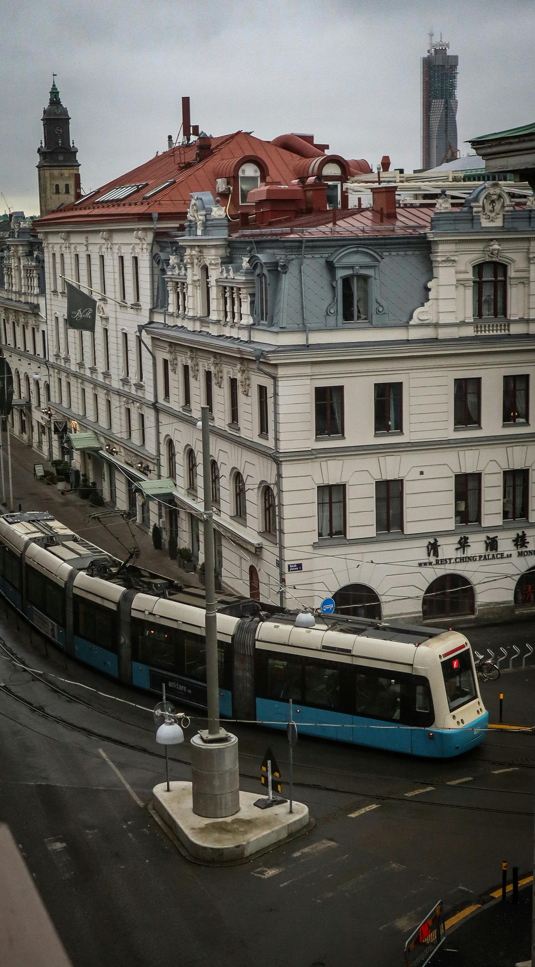 Free Tram navigating through historic buildings in Gothenburg, Sweden. Overcast day in the city. Stock Photo