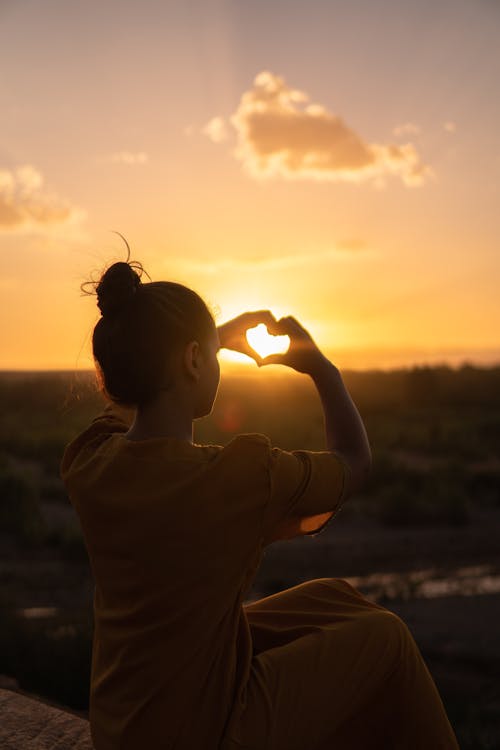 Mujer Sentada Mientras Muestra Las Manos Del Signo Del Corazón