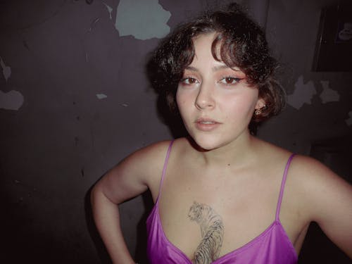 Young Woman with a Tattoo on Her Chest Standing in an Abandoned Building 