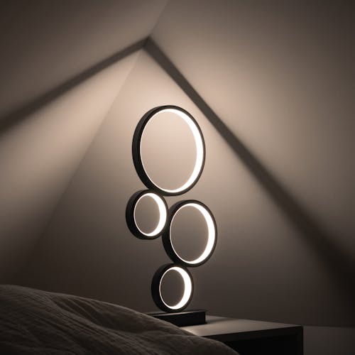 A lamp with circles on it is sitting on a bed