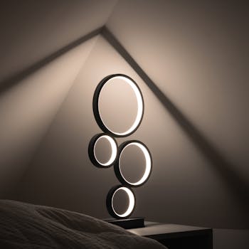 Elegant minimalist lamp with circular design, casting soft light in a dim, modern room.