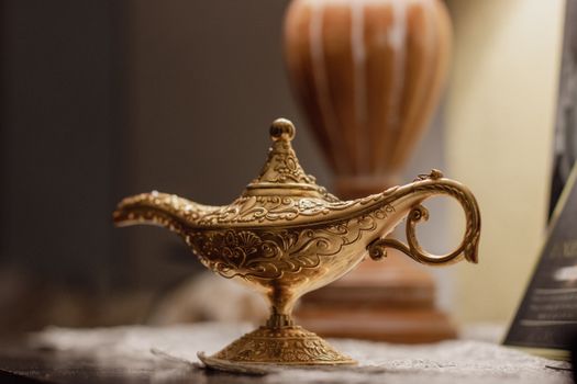 Close-up of a golden vintage genie lamp as a decorative piece indoors.