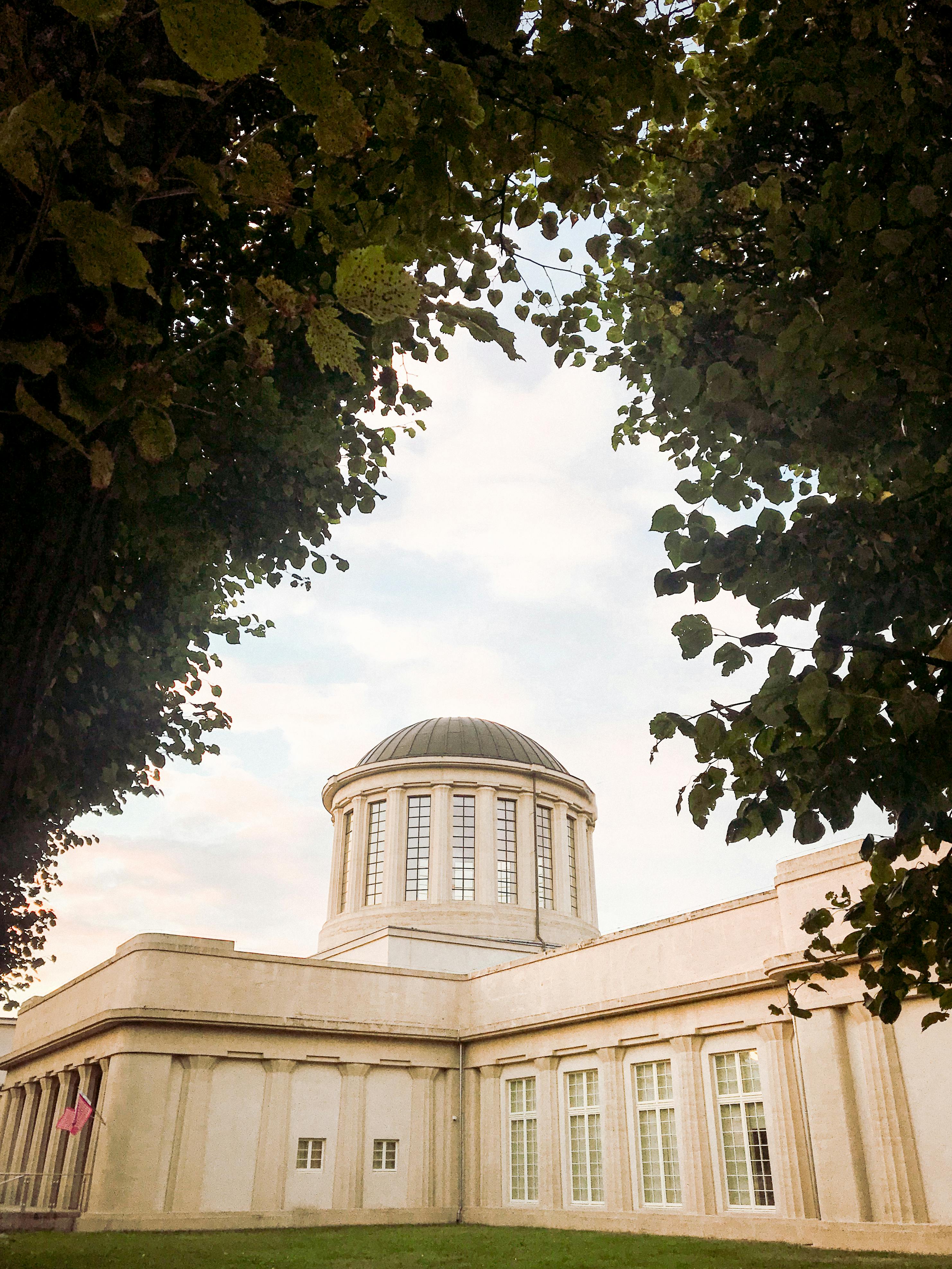 A stunning architectural dome in Wrocław, Poland framed perfectly by lush green trees.