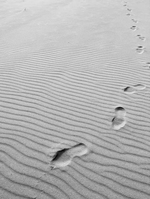 Grayscale Photo of Footprints on Sand