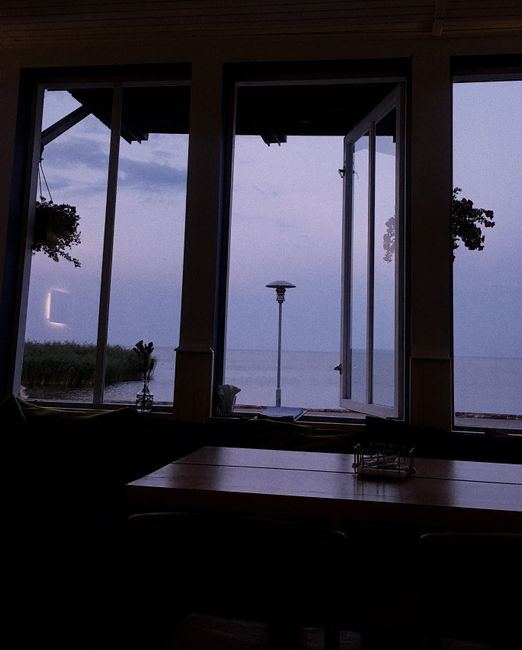 Relaxing indoor scene with open window view of the Baltic Sea at twilight, capturing serene ocean vibes in Nida, Lithuania.