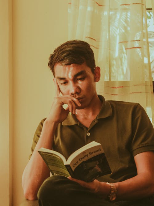 Young Man Sitting and Reading a Book 