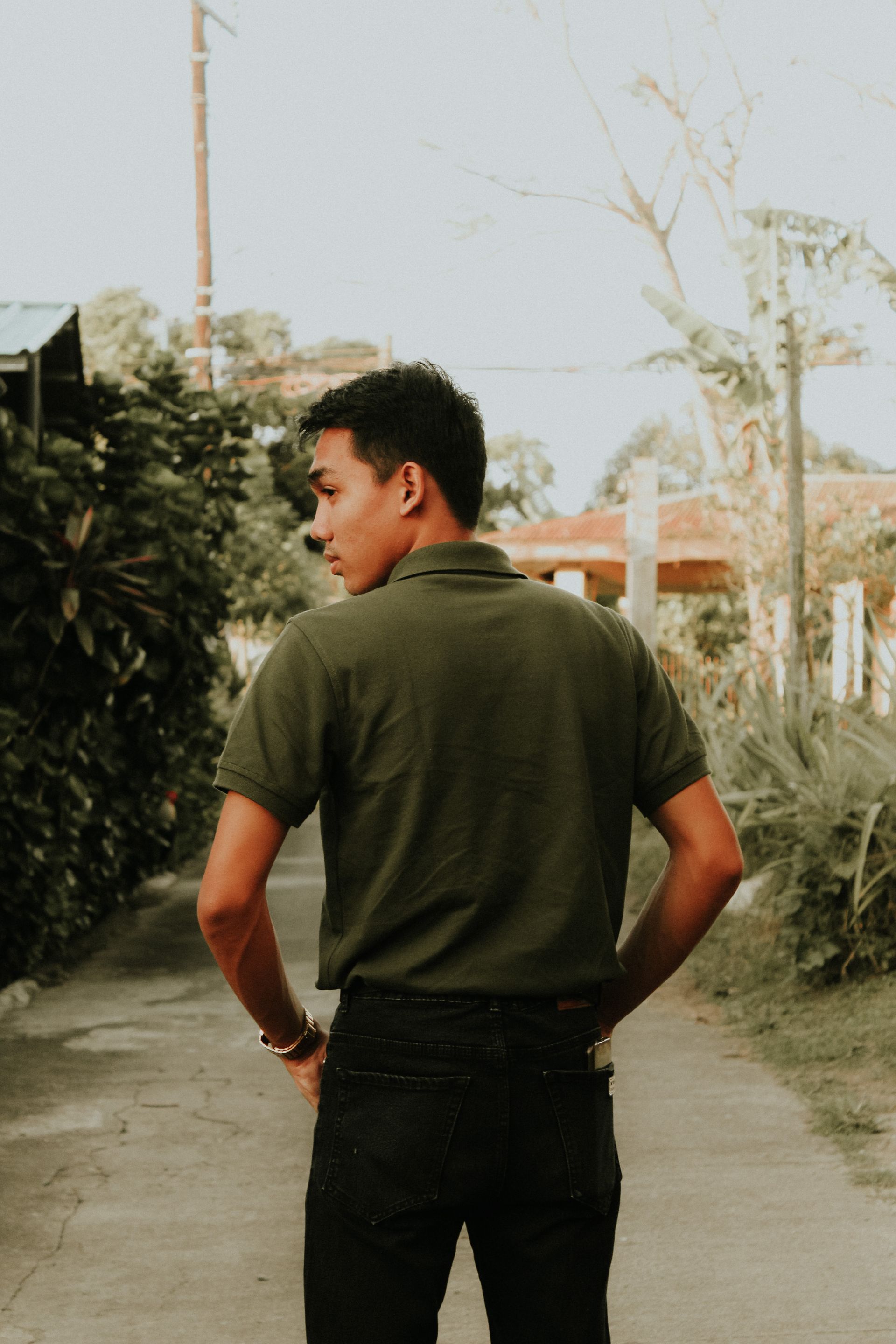 Back view of a man in jeans with his hands in his pockets outdoors