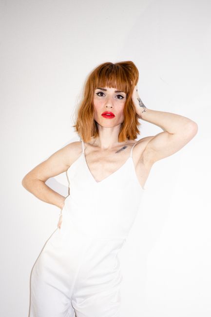 Striking portrait of a redhead woman in white, showcasing elegant fashion style.