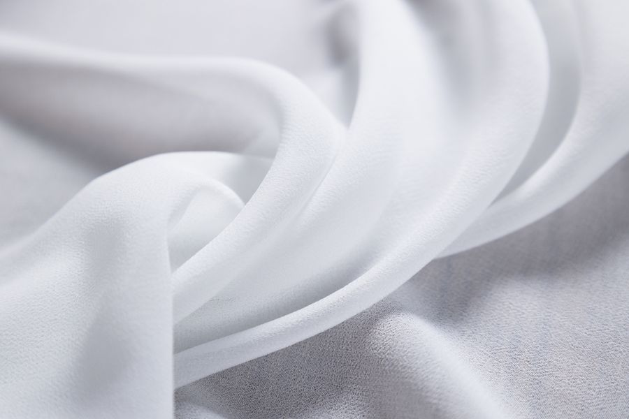 Close-up of a smooth, flowing white fabric texture. Ideal for fashion and textile concepts.