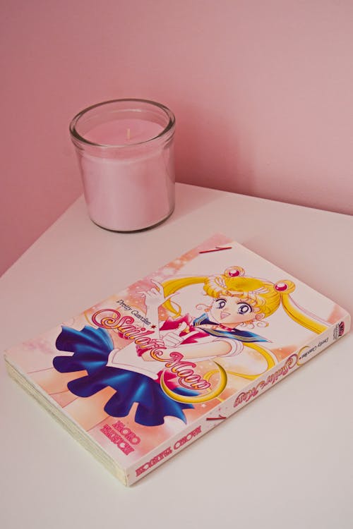 A Book and Candle on a White Table next to a Pink Wall
