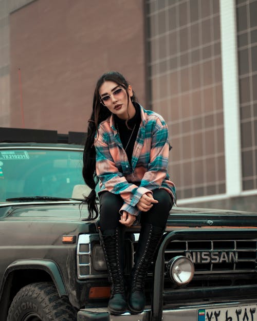 A Fashionable Woman Sitting on the Hood of a Pickup Truck