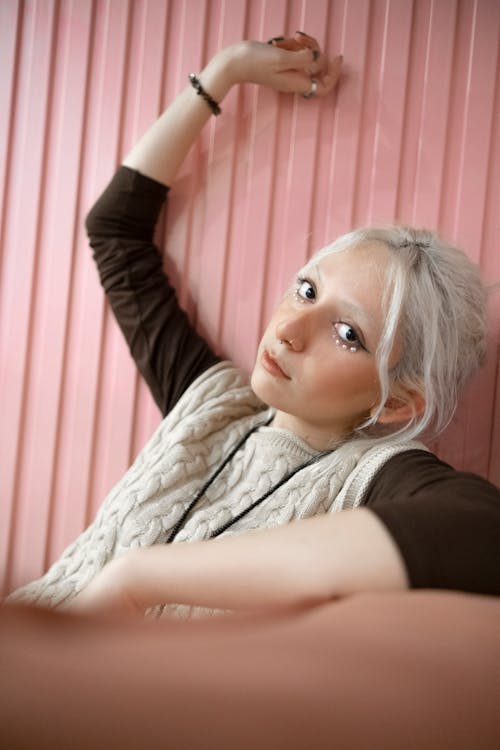 Young Woman Sitting on the Background of a Pink Wall 