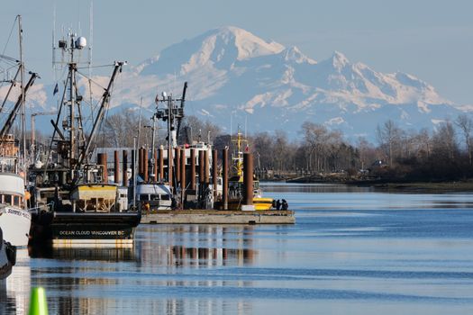 Beautiful harbor with fishing boats, snowy mountains, and a calm river in Vancouver.