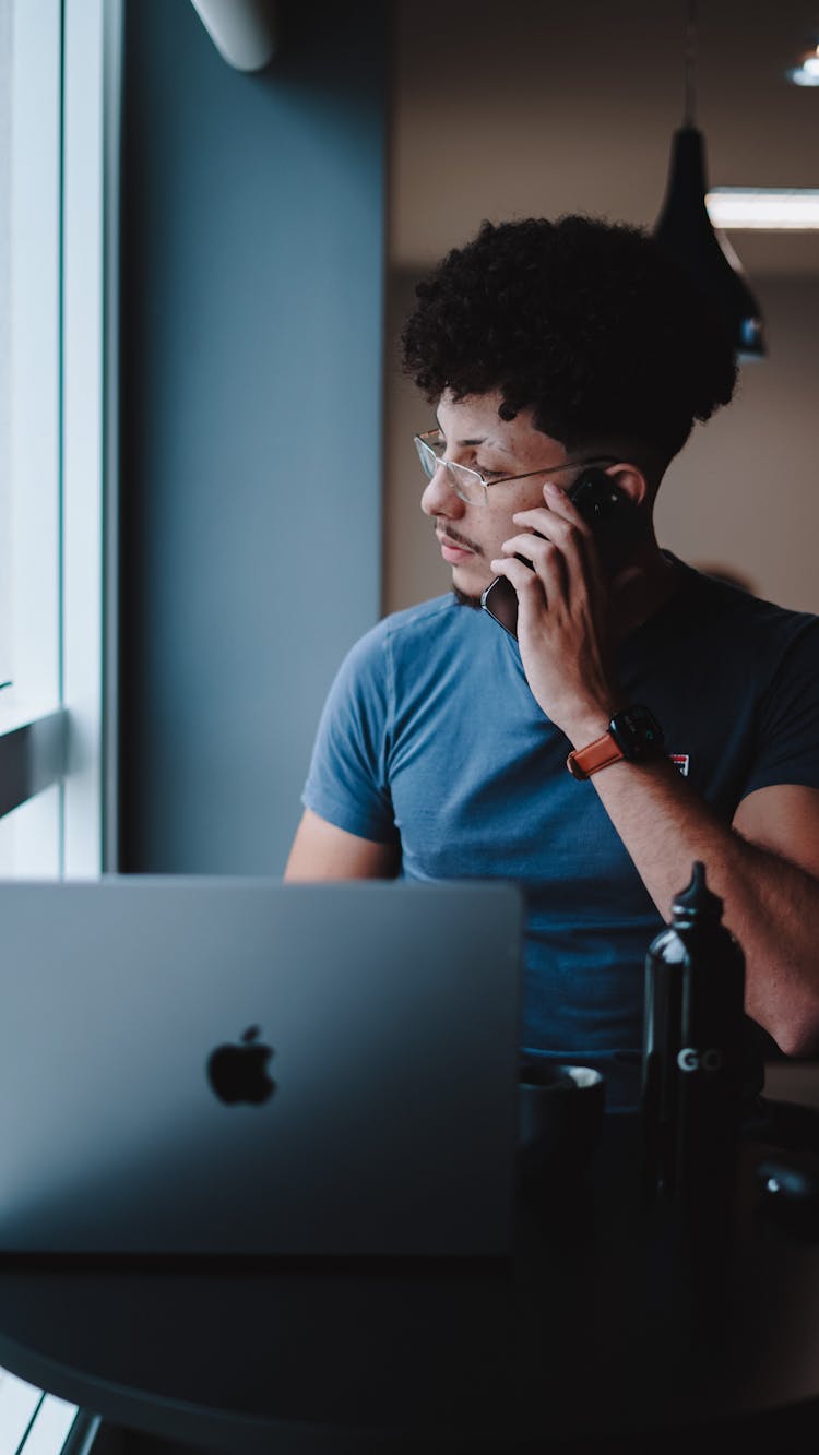 Man Working On Laptop Talking On Cellphone