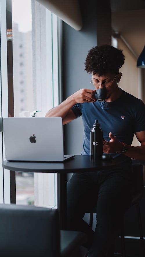Man Drinking Coffee Working on Laptop