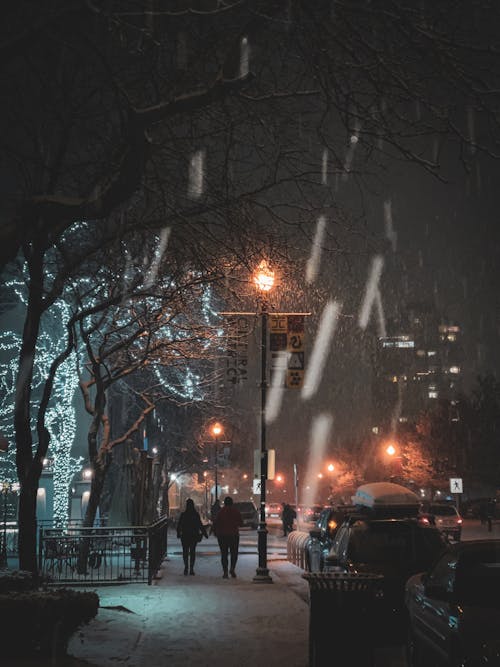 People Walking on Sidewalk in Town in Winter at Night