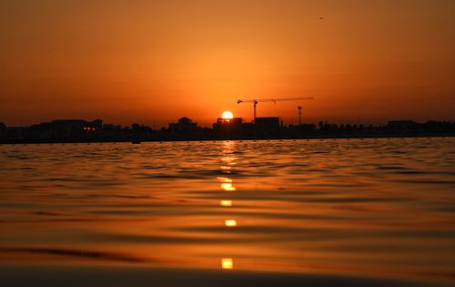 Free Serene sunset with silhouette of cityscape by the calm sea, perfect for tranquil moments. Stock Photo