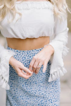 Elegant style featuring a floral skirt and white crop top, highlighted by an engagement ring.
