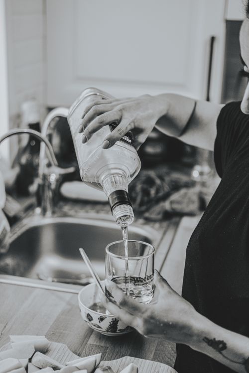 Free A monochrome scene capturing a drink being poured into a glass in a kitchen setting. Stock Photo