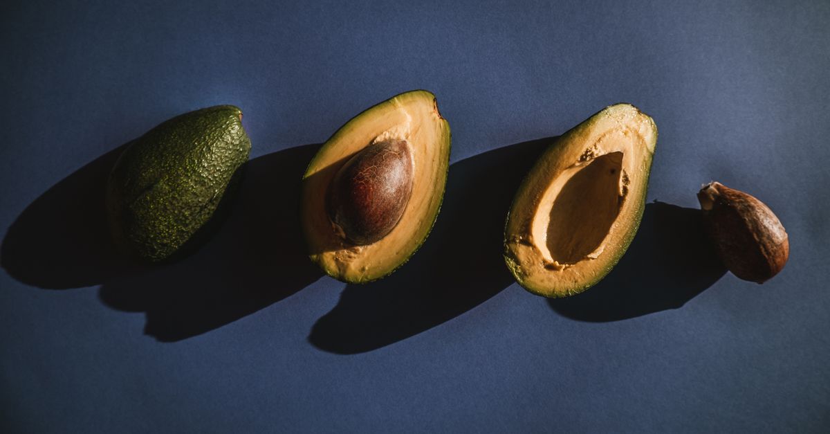 Overhead view of fresh avocados, halved and whole, with shadow play on a dark surface. - Evidence evidence guide for avocado cognition randomized trial