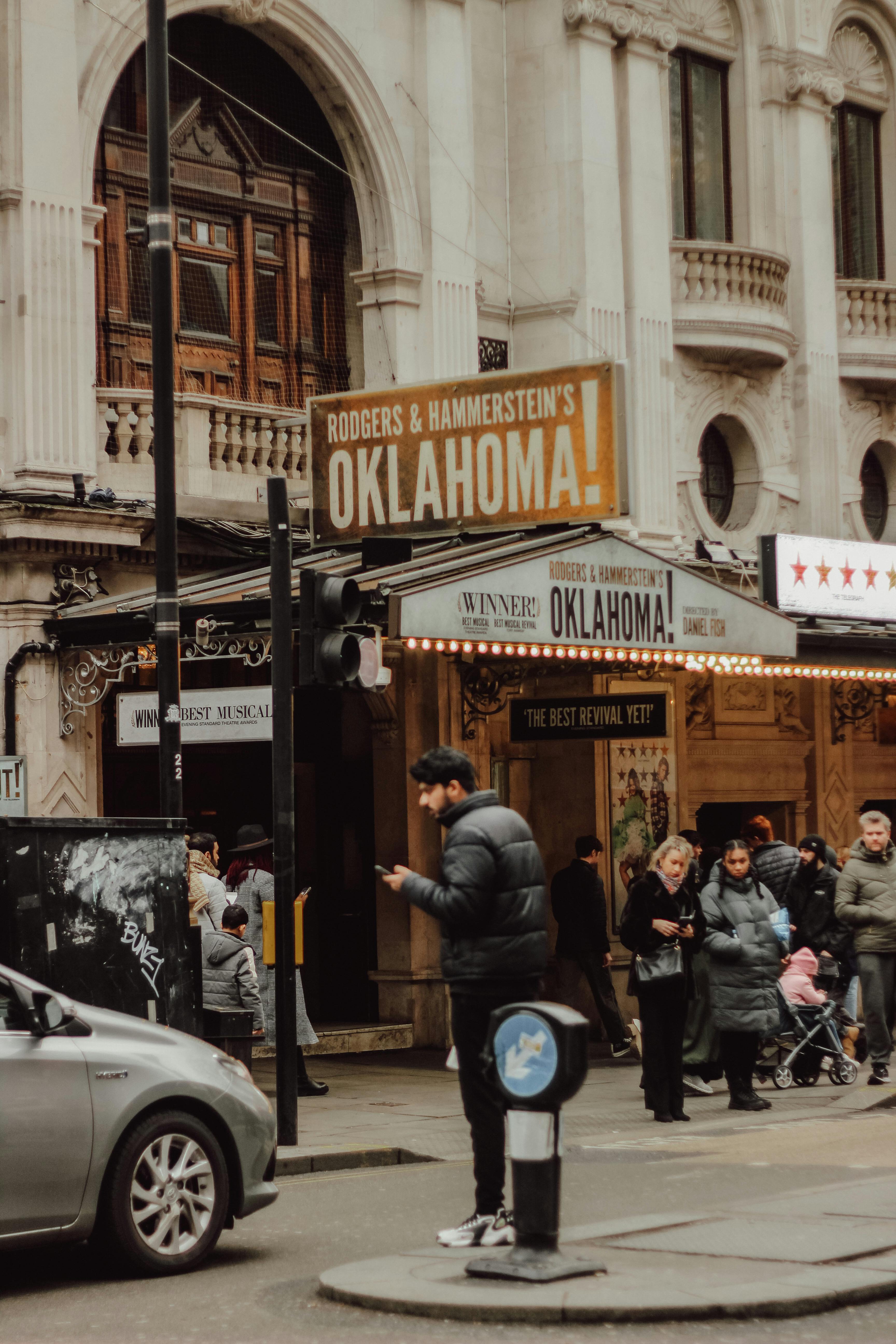 Free Urban street scene in London featuring a theater facade and diverse pedestrians. Stock Photo