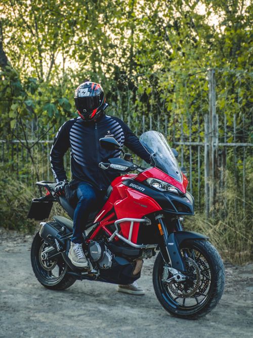 Free A motorcyclist wearing full gear sits on a red Ducati motorcycle outdoors. Stock Photo
