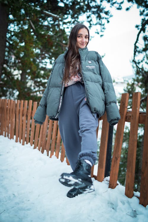 Smiling Woman Standing next to Wooden Railing in Winter