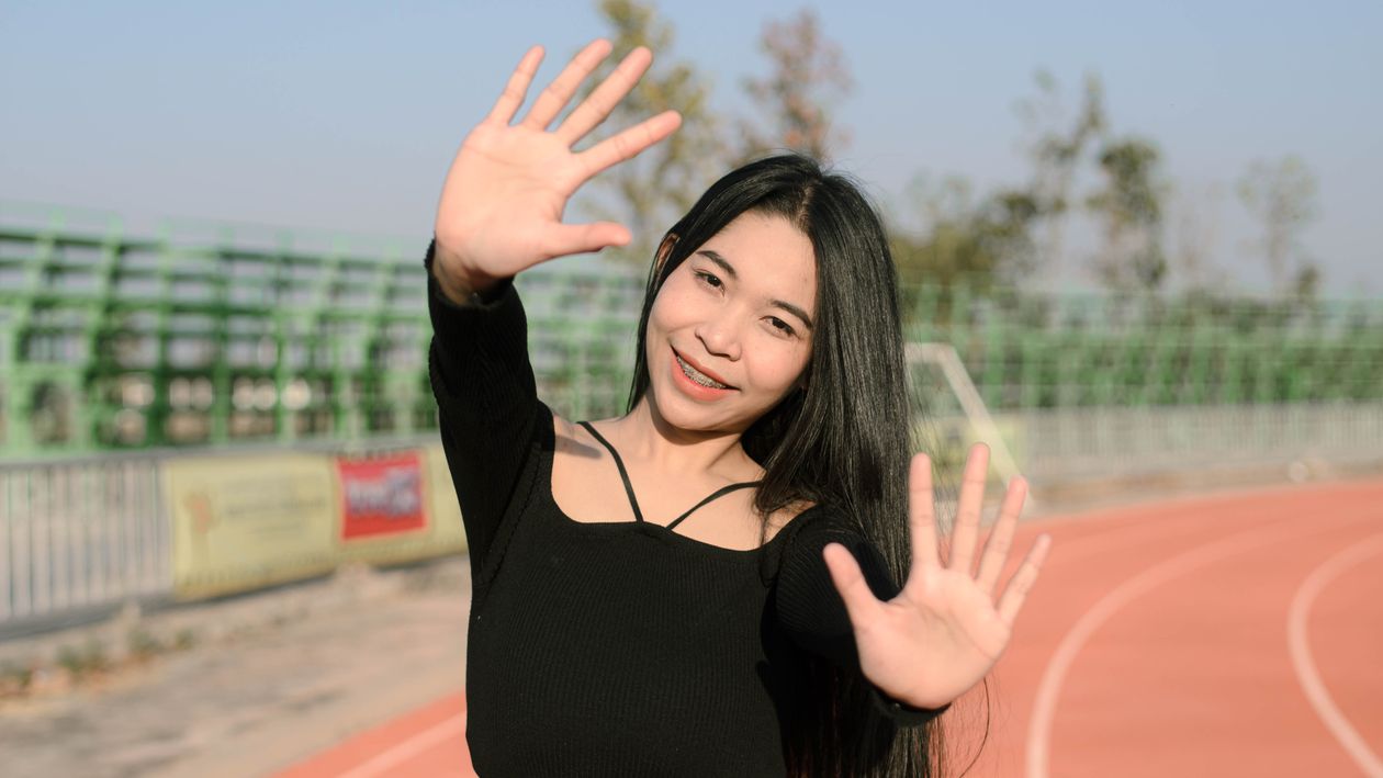 A smiling Thai woman raising her hands in greeting