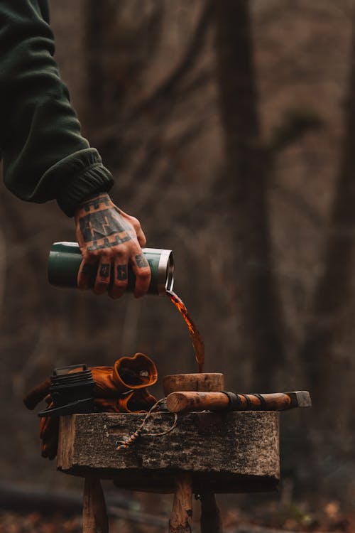 Man Hand with Tattoos Pouring Coffee from Thermos to Cup