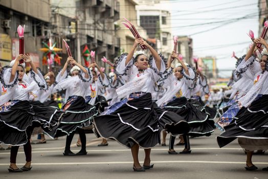 Dynamic street parade showcasing women in traditional attire performing a cultural dance.