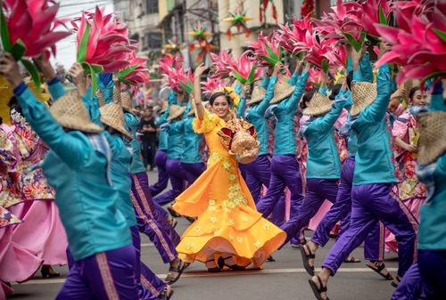 Free Colorful street festival with dancers in traditional clothing and large floral displays. Stock Photo