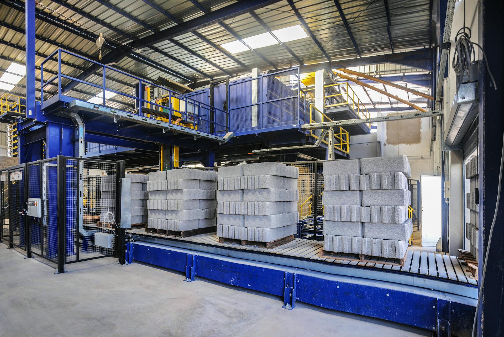 Modern logistics warehouse in Fès with stacked concrete blocks and industrial equipment on display.